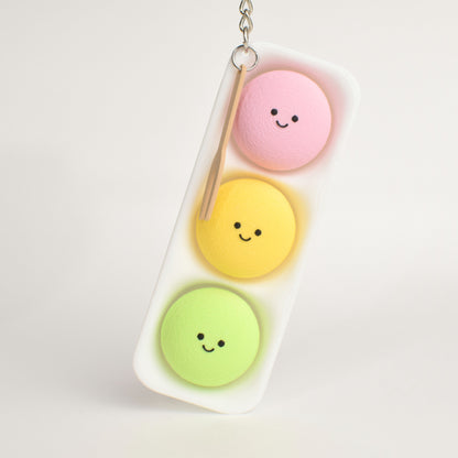 A cute keychain shaped like a mini mochi ice cream with three smiling pastel mochis in pink, yellow, and green, hanging from a silver metal chain.