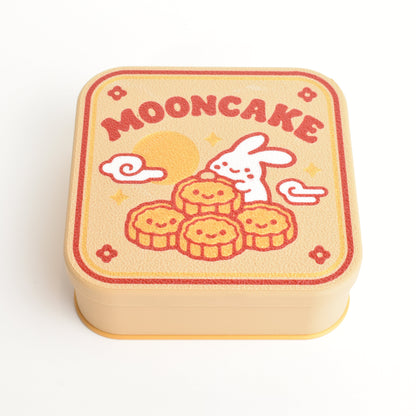 Cute Mid Autumn mooncake gift box with festive illustrated lid design. A square mooncake box with rounded corners, featuring a cute illustration of a white rabbit eating mooncakes under a full moon, with the word 'MOONCAKE' printed in red at the top. The box is photographed on a clean white background.