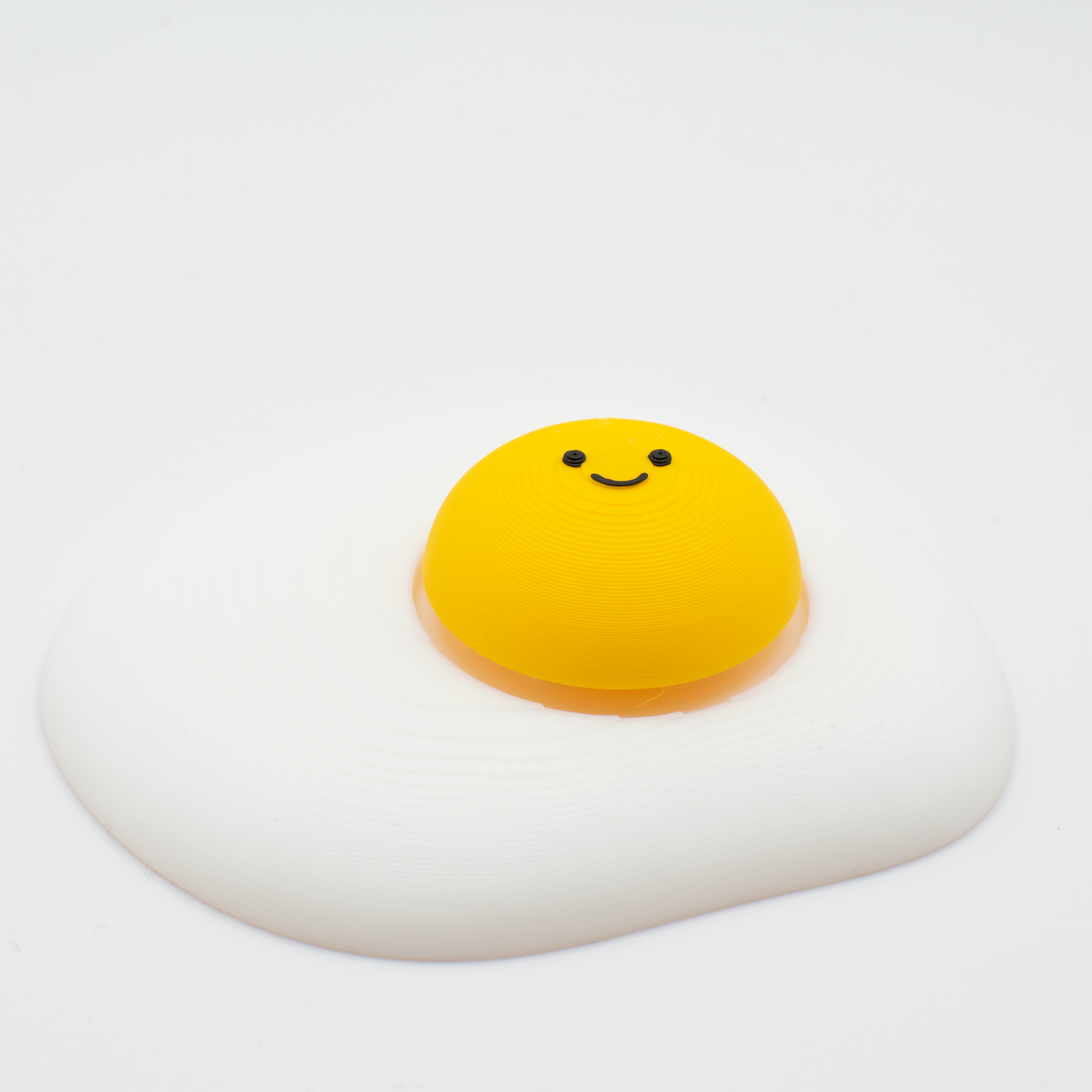 Side view of an original fried egg fidget clicker desk toy