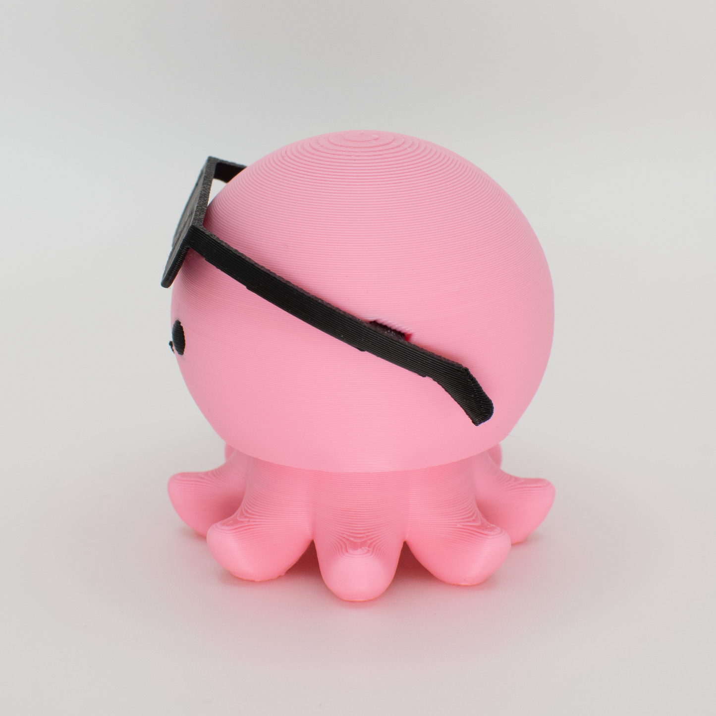 Side view of an original pink octopus with sunglasses mechanical switch fidget toy