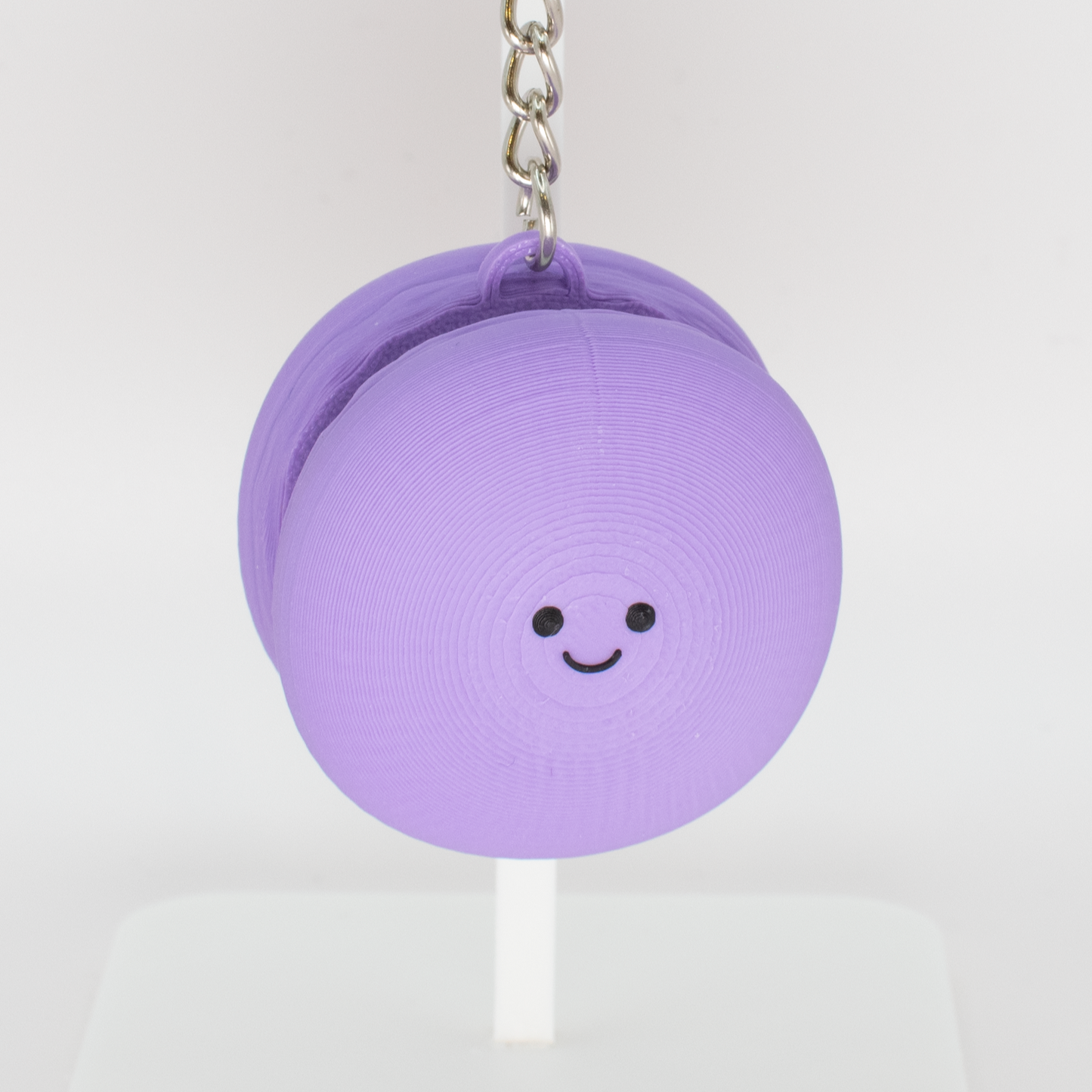 Cute purple macaron fidget clicker keychain with a smiling face