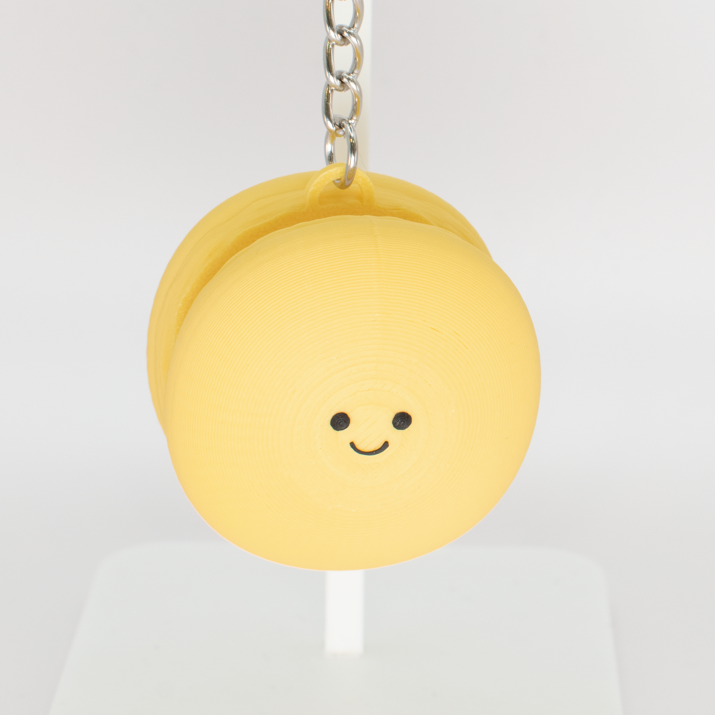 Cute yellow macaron fidget clicker keychain with a smiling face
