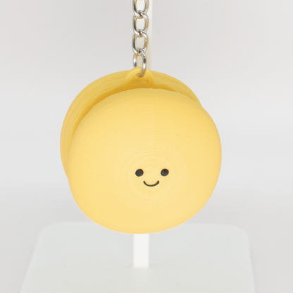 Cute yellow macaron fidget clicker keychain with a smiling face