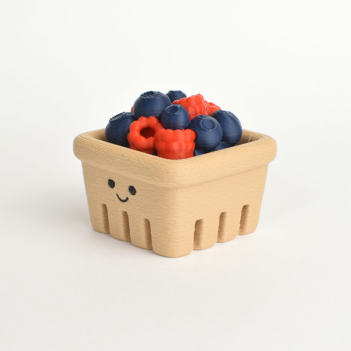 A small beige basket-shaped container filled with blueberries and red berries, photographed on a clean white background.