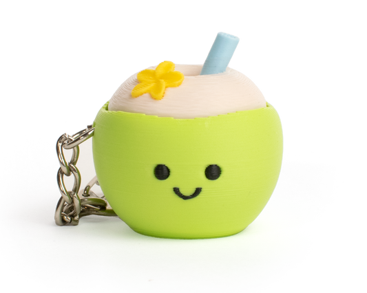 A cute, small green coconut-shaped keychain or bag charm with a smiling face, a light blue straw, and a small yellow flower on top, shown on a plain white background.