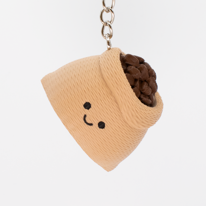 Keychain with a beige container holding brown coffee beans on a white background