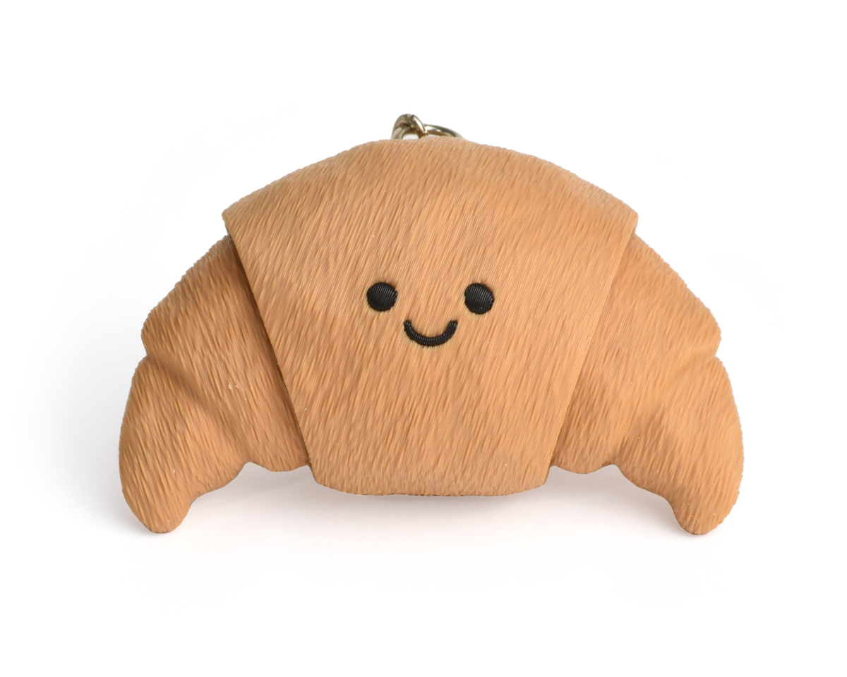 a cute croissant clicker keychain with smiley face, with two clickable ends