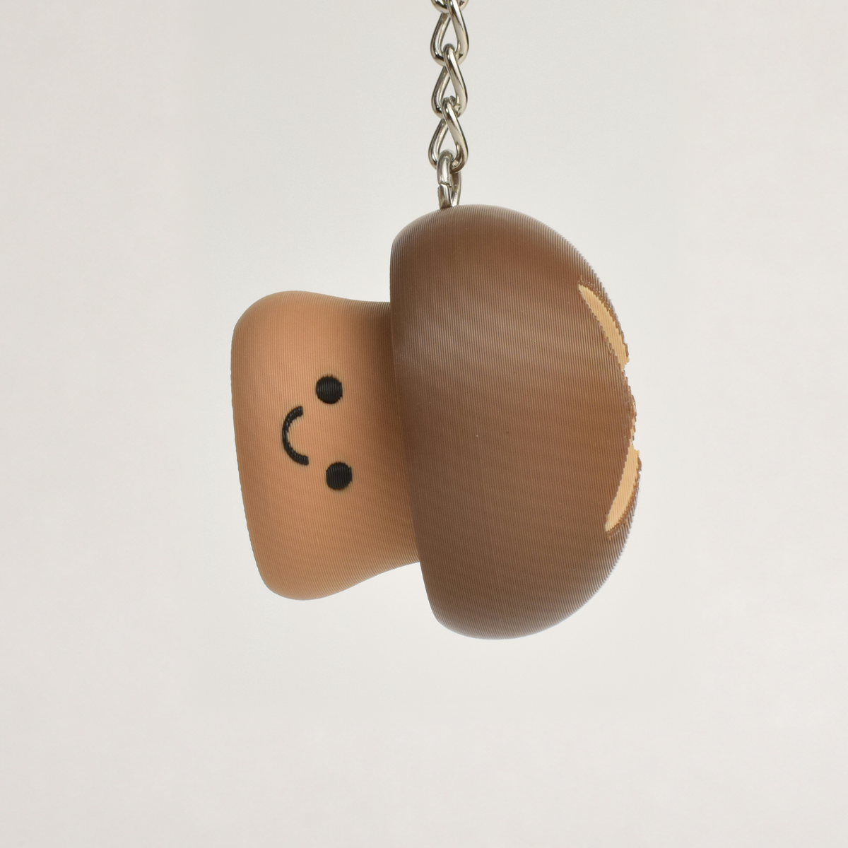 Cute brown mushroom clicker keychain with a smiling face hanging as a fun bag or key accessory