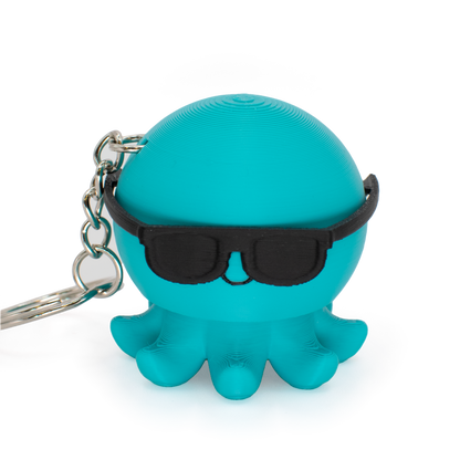 Turquoise octopus fidget clicker keychain with black sunglasses on a light gray background