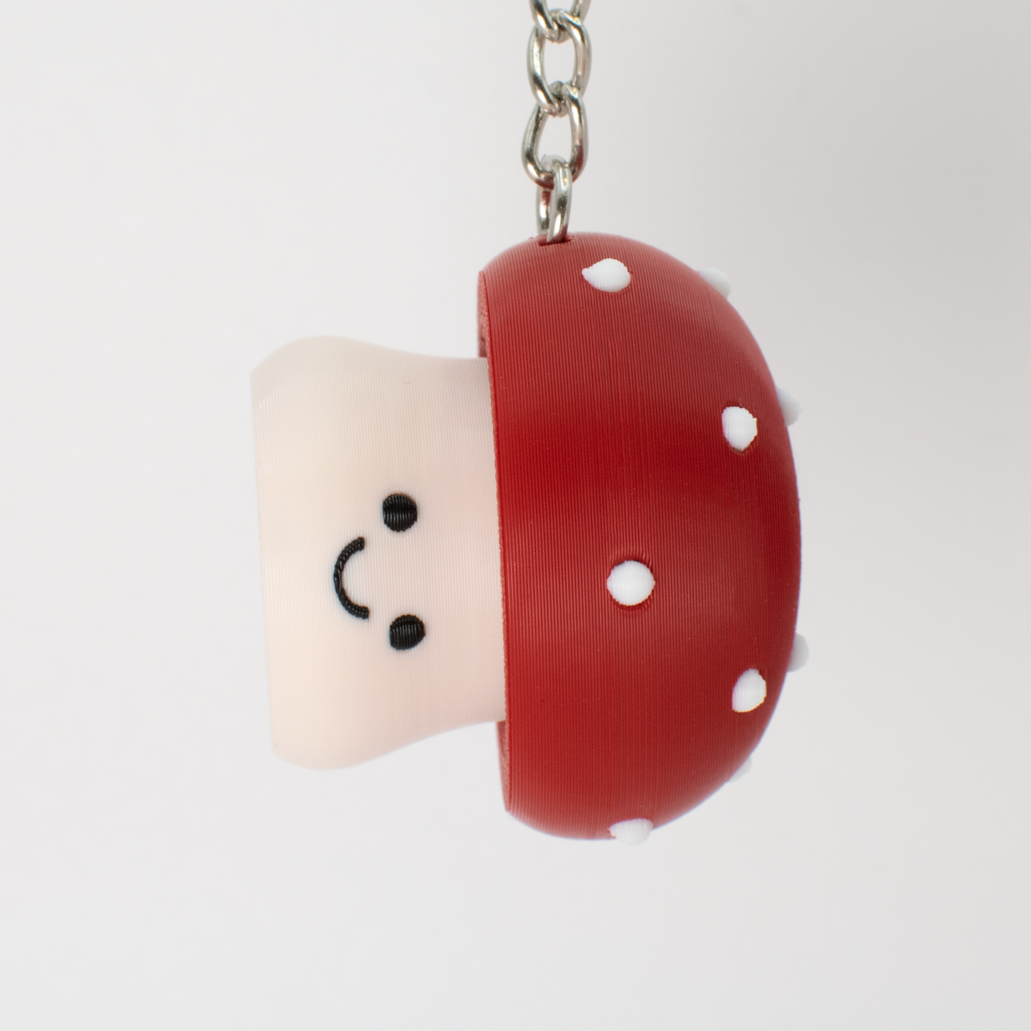 Cute toxic mushroom clicker keychain with a smiling face hanging as a fun bag or key accessory