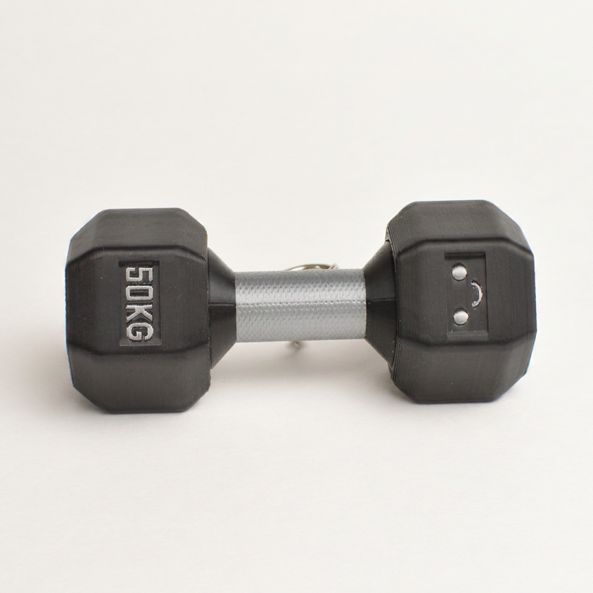 A "50 kg" hexagonal dumbbell clicker with black rubberized looking ends and a textured silver metal handle, shown on a clean white background.