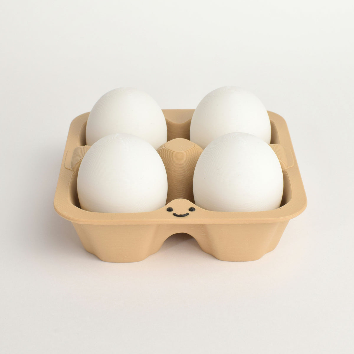 fidget clicker styled as four white eggs arranged in a light brown cardboard egg carton with a small smiley face printed on the front, set against a clean white background.