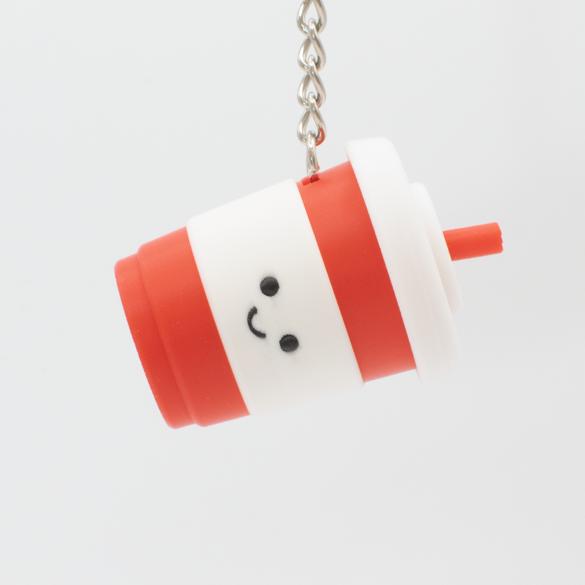 Keychain shaped like a cartoon cup with a smiling face on a white background