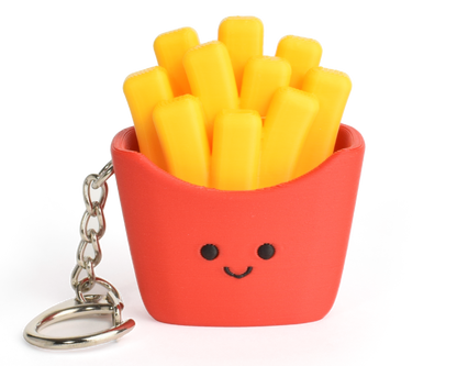 A small novelty keychain shaped like a basket of French fries. The basket is bright red with a simple black face, filled with yellow fries, and attached to a silver metal key ring on a plain white background.