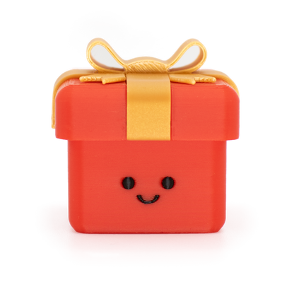 clicker styled as a small red gift box with a smiling face on the front, topped with a gold ribbon and bow, isolated on a white background.