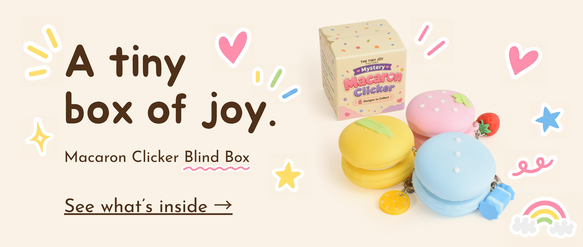 a banner that has "a tiny box of joy" and "macaron clicker blind box" texts on it, and it shows the blind box and three macaron clicker designs