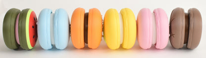 A row of colourful macaron clickers lined up horizontally on a white studio background.