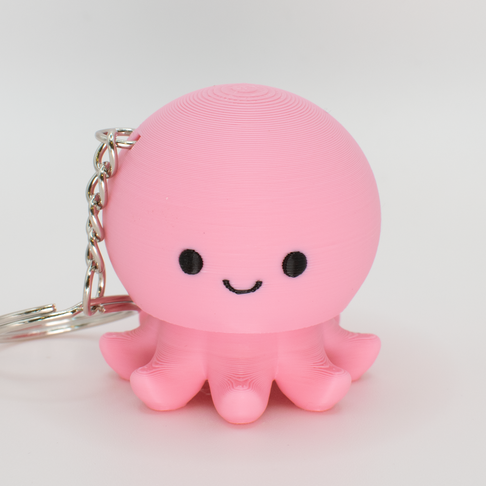 pink octopus fidget clicker keychain with a smiley face