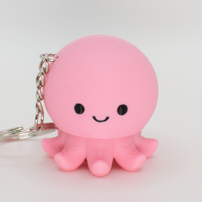 pink octopus fidget clicker keychain with a smiley face