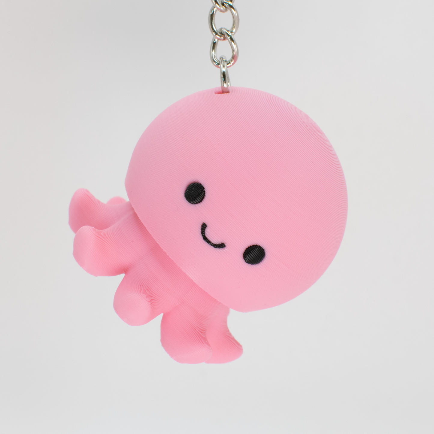 Pink octopus fidget toy keychain with a smiley face on a light gray background