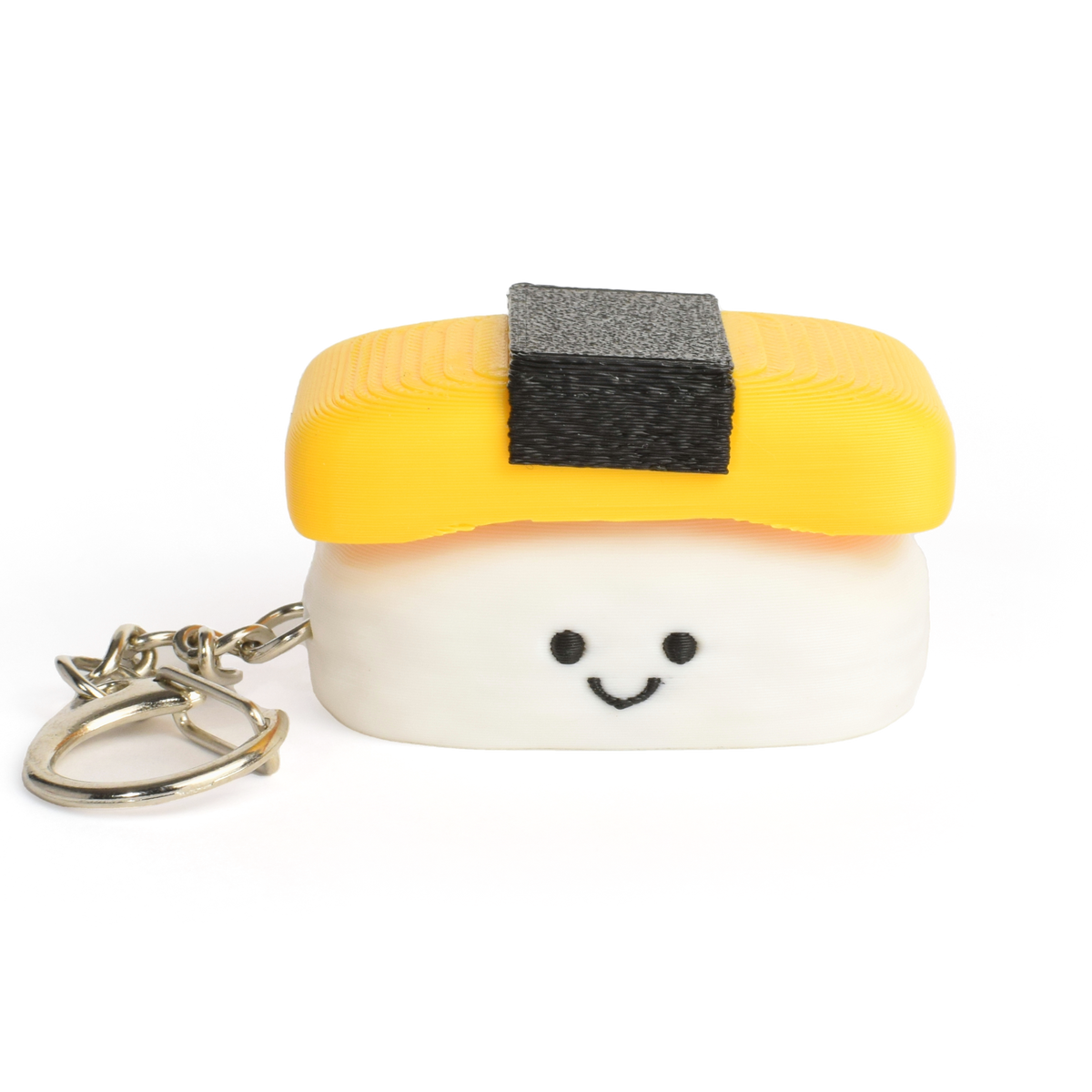 A small sushi-shaped clicker keychain with a smiling face, featuring a yellow egg top and a white rice base, attached to a silver metal key ring on a plain white background.
