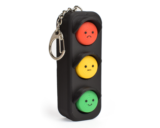 side view of a traffic light fidget clicker, black case with red, yellow, and green buttons resembling a traffic light