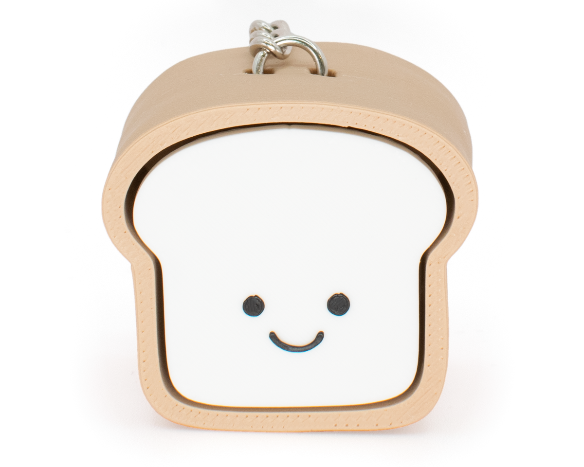 A toy clicker designed to look like a loaf of bread with a smiling face, primarily in beige and white colors.