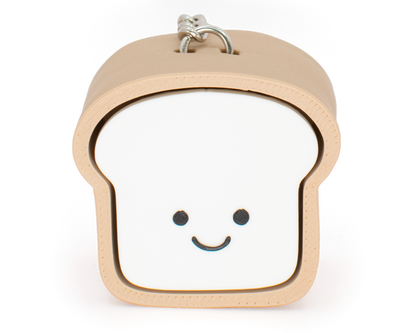 A toy clicker designed to look like a loaf of bread with a smiling face, primarily in beige and white colors.