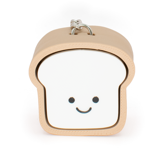 A toy clicker designed to look like a loaf of bread with a smiling face, primarily in beige and white colors.