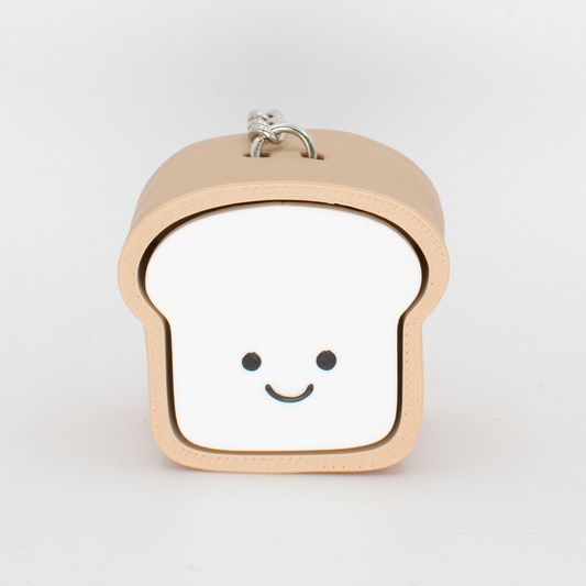 A toy clicker designed to look like a loaf of bread with a smiling face, primarily in beige and white colors.