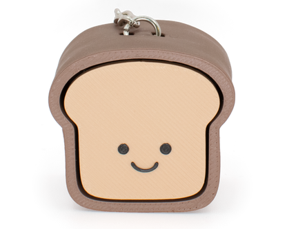A fidget clicker designed to look like a loaf of bread with a smiling face, primarily in beige and brown colors.