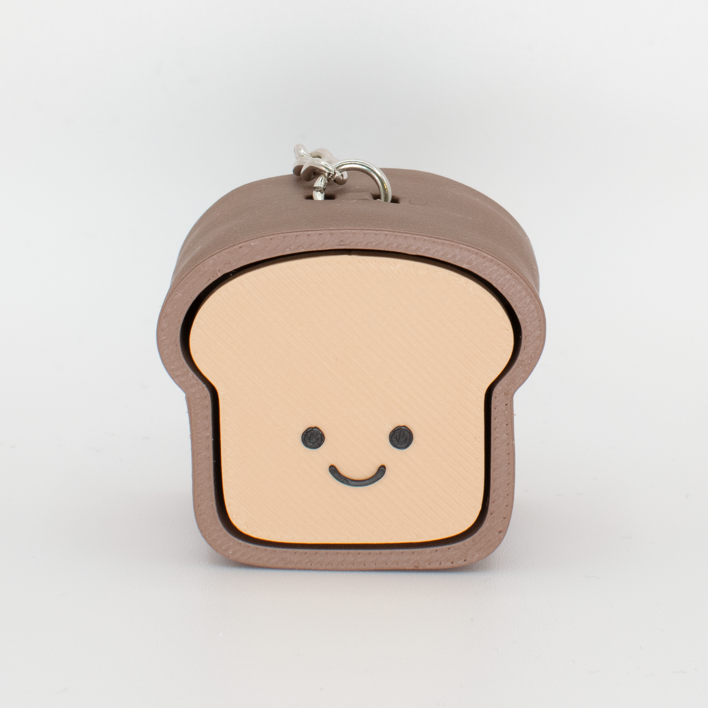 A fidget clicker designed to look like a loaf of bread with a smiling face, primarily in beige and brown colors.