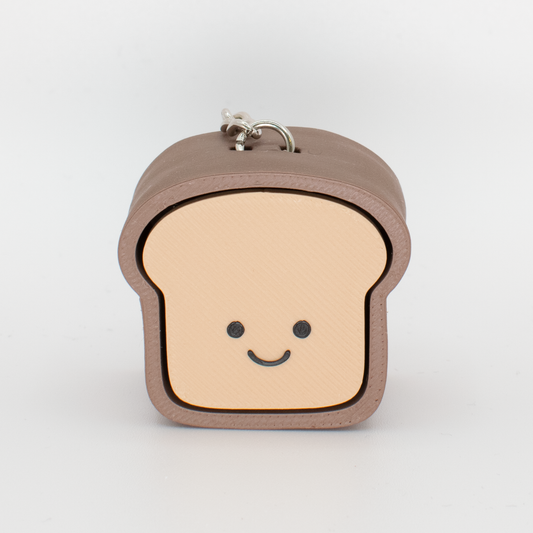 A fidget clicker designed to look like a loaf of bread with a smiling face, primarily in beige and brown colors.
